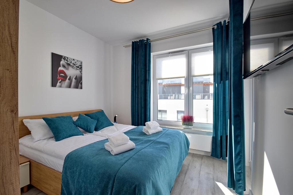 - une chambre avec un lit doté de draps bleus et une fenêtre dans l'établissement Apartament Nadmorskie Tarasy SPA Deluxe, à Kołobrzeg