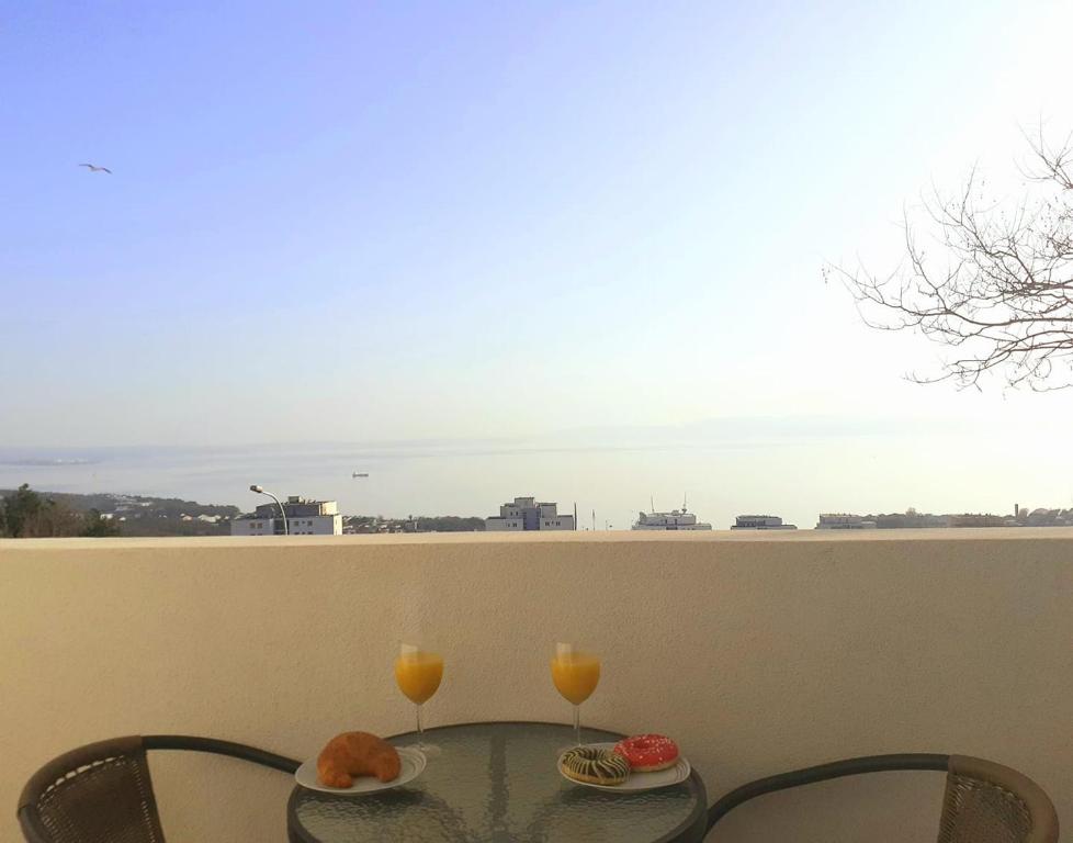 una mesa con 2 vasos de zumo de naranja en el balcón en Apartment Lilly, en Rijeka