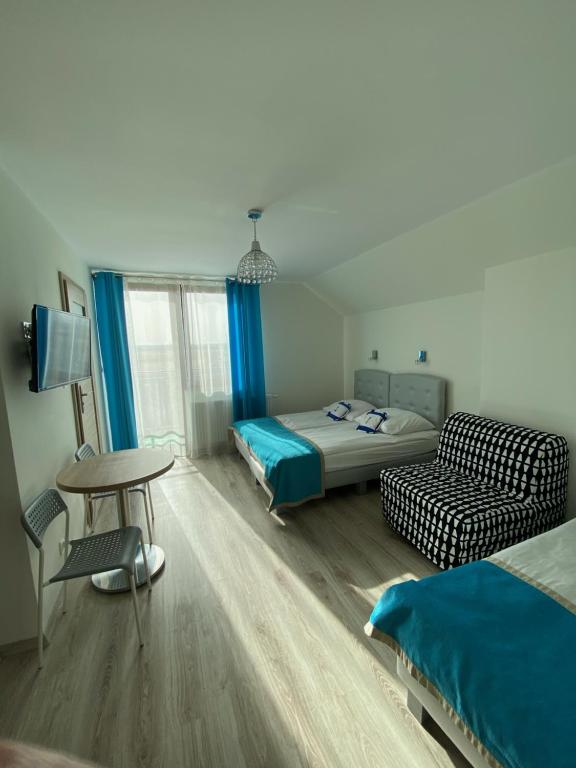 a room with two beds and a table and a couch at Błękitna Laguna 2 in Rewa