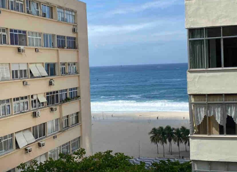 a view of the beach from between two buildings at Apartamento c/vista p o mar no Leme in Rio de Janeiro