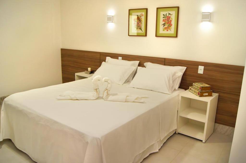 a large white bed with two stuffed animals on it at Hotel Flor Da Chapada in Itaberaba