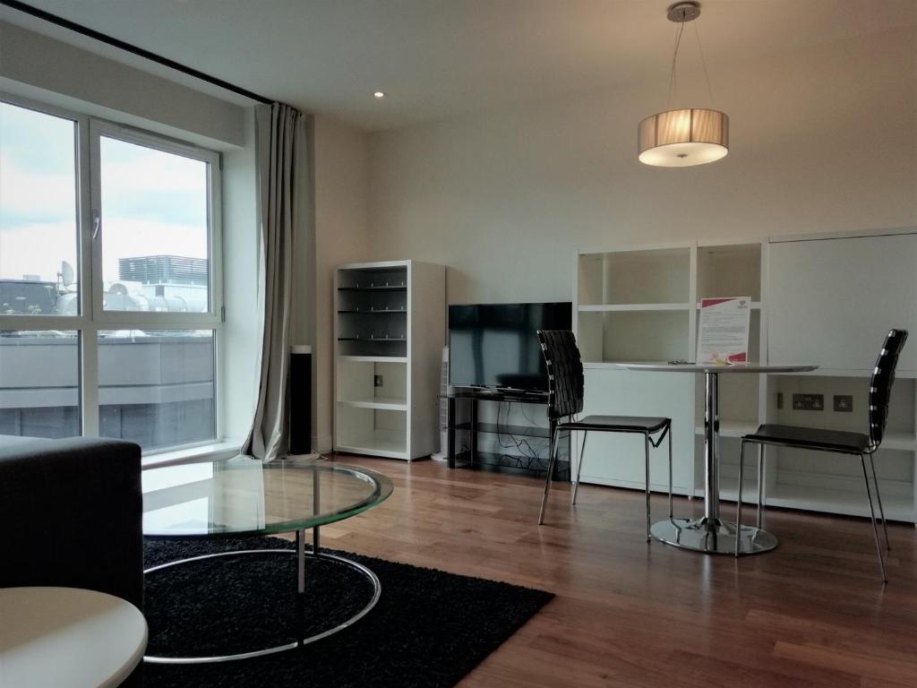 een woonkamer met een glazen tafel en een bureau bij Barbican Serviced Apartments in Londen