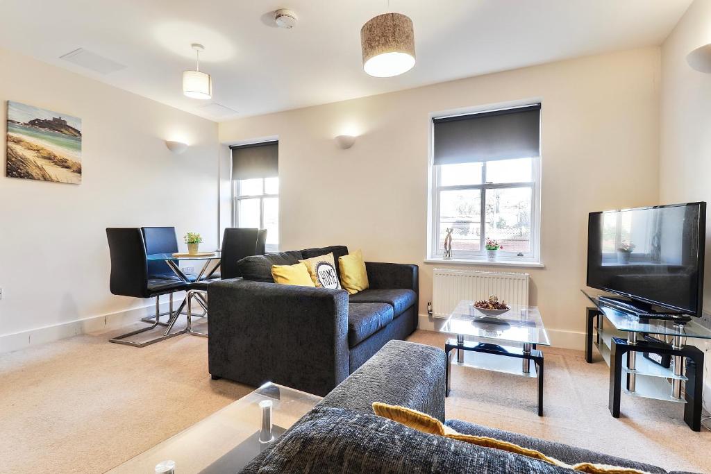 a living room with a couch and a tv at Sapphire Serviced Apartment in Chelmsford