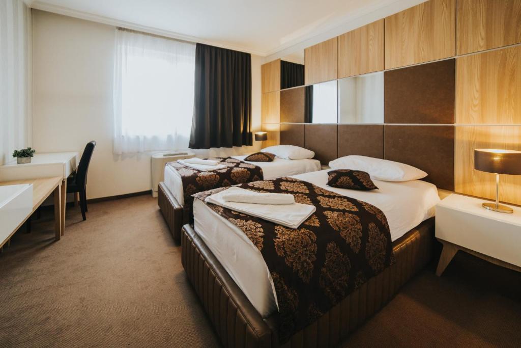 a hotel room with two beds and a desk at Hotel Brcko Gas Doboj in Doboj