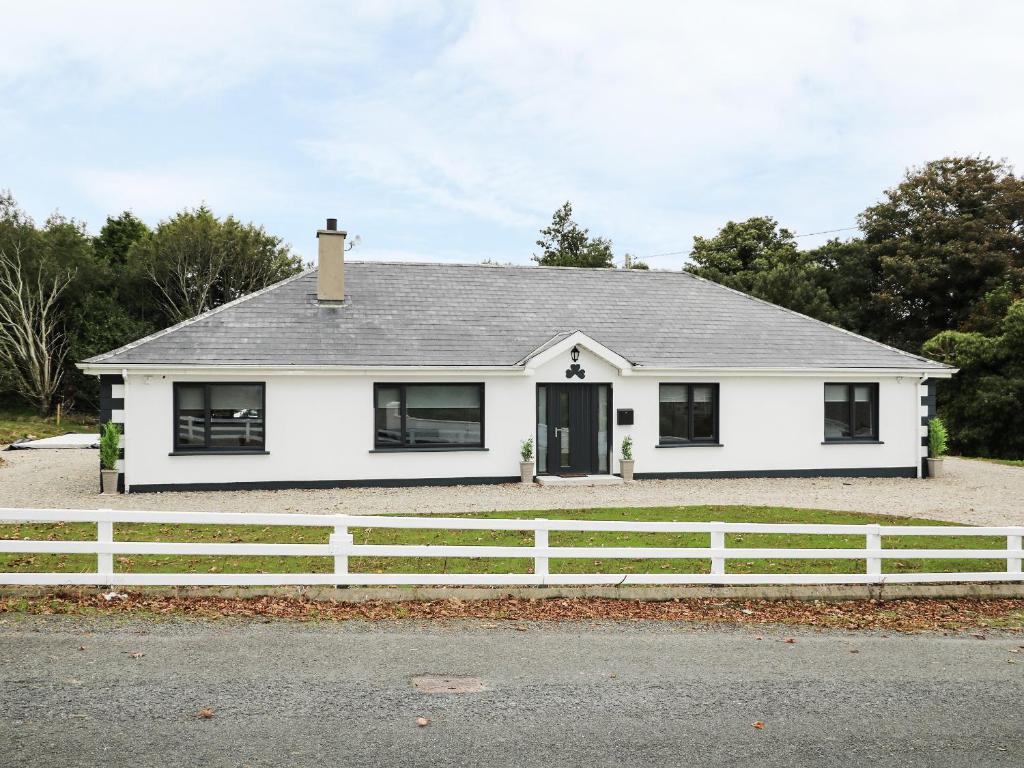 una casa blanca con una valla blanca en Gatehouse en Moville