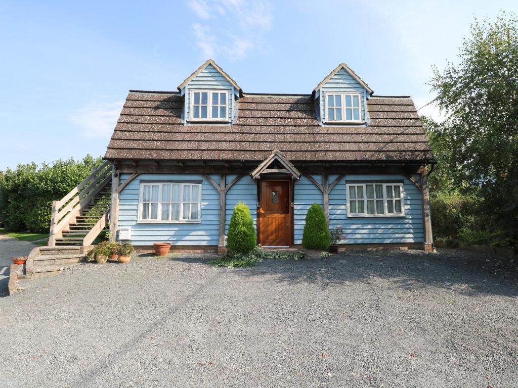 niebieski dom z drewnianymi drzwiami i podjazdem w obiekcie Flink's Barn w mieście Great Dunmow