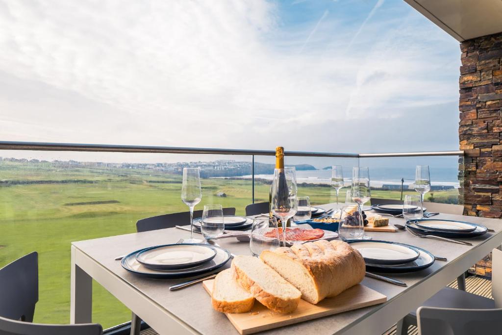 a table with bread and wine glasses on a balcony at Newquay Fistral Beach View in Newquay