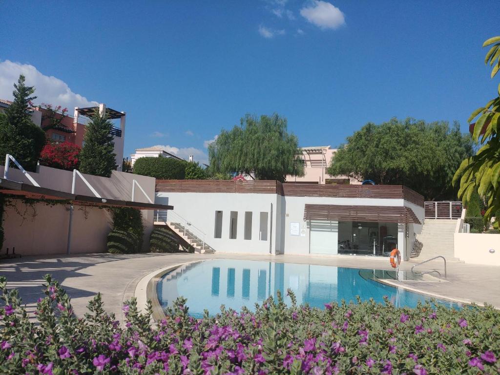 una piscina frente a una casa con flores púrpuras en Amathousa Coastal Heights D202 en Limassol