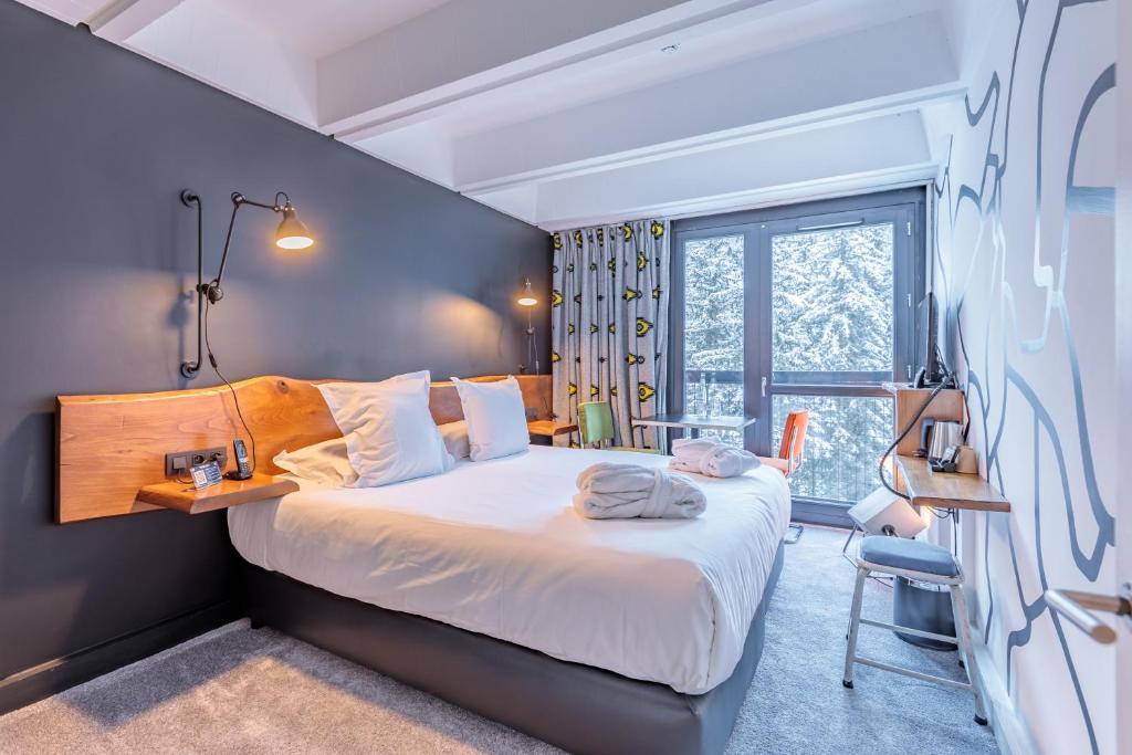 Un dormitorio con una cama grande y una ventana en Totem, Friendly Hotel & Spa en Flaine