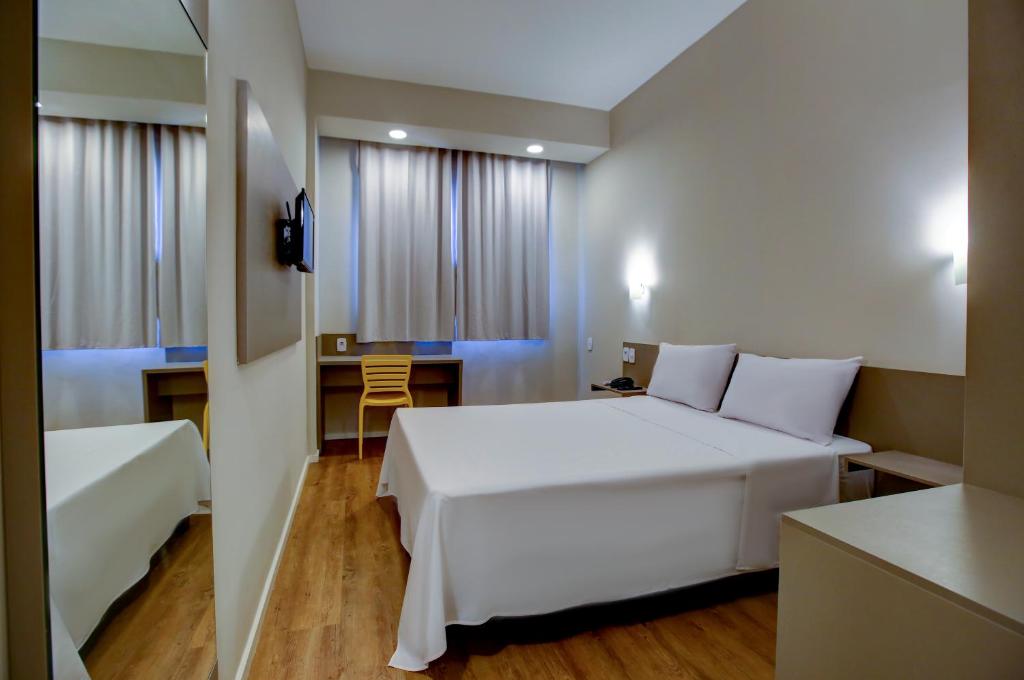 a bedroom with a large white bed and a desk at Transamerica Fit Rondonopolis in Rondonópolis