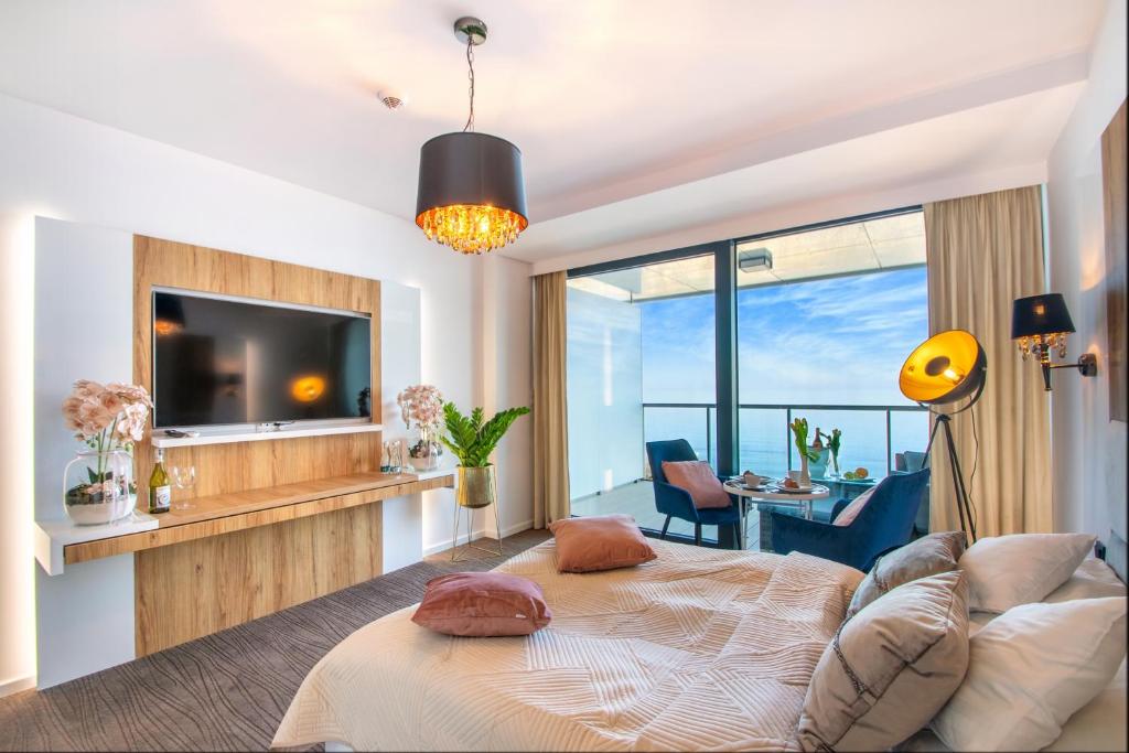 a living room with a bed and a tv at NORTH Apartments, SunSetView 507 in Kołobrzeg