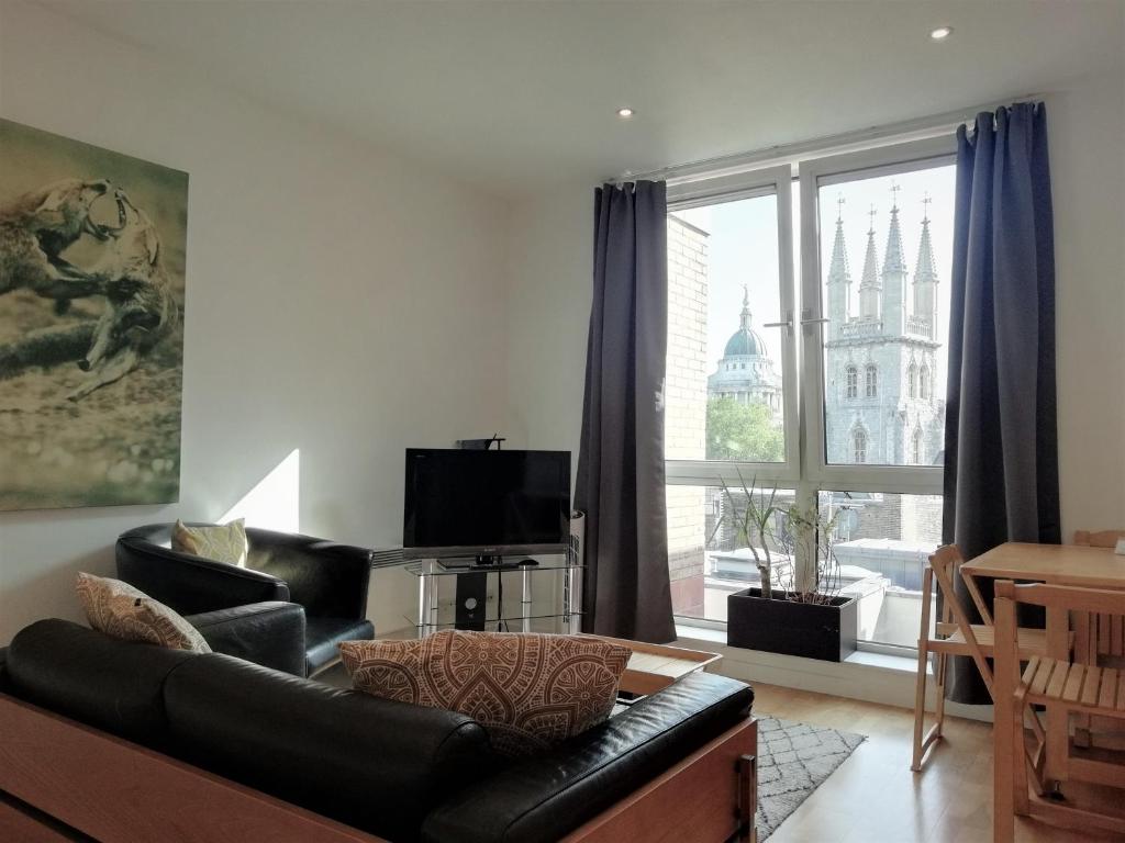 a living room with a black leather couch and a large window at Still Life St Paul's Executive in London