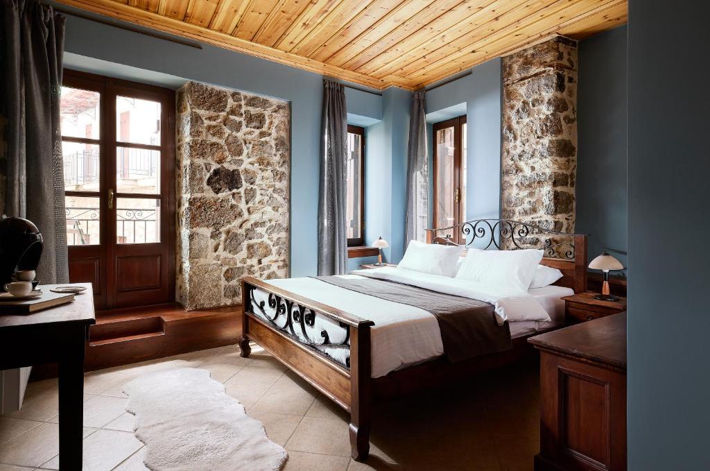 a bedroom with a bed and a stone wall at Stone Suites by White Hills in Arachova