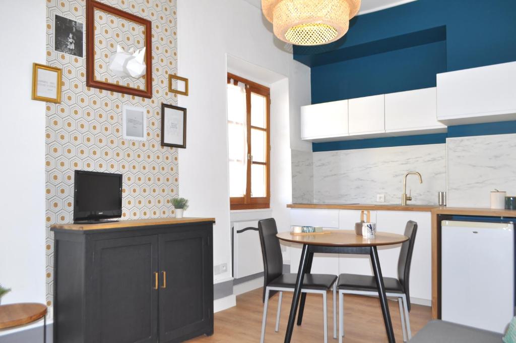 - une cuisine avec des murs bleus et blancs, une table et des chaises dans l'établissement SEJOURAIXLESBAINS - Appartements Confidence hyper centre calme, à Aix-les-Bains