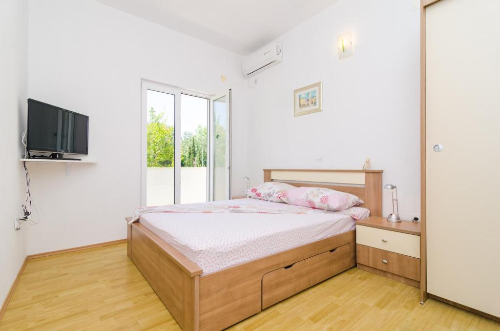 a bedroom with a bed and a flat screen tv at Rooms &amp; Apartments Barišić in Mlini