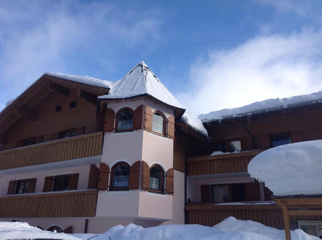 a building with a clock tower in the snow at NRH Laurin Karersee in Nova Levante