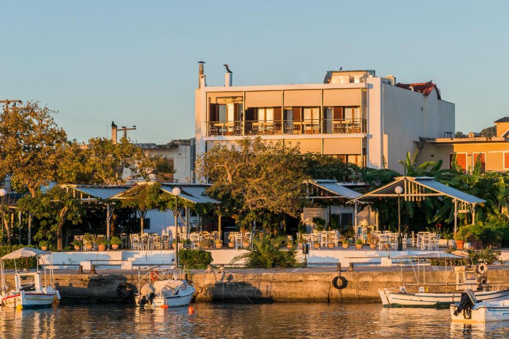 Akroyali Hotel & Villas في أيوس أندرياس ميسينياس: مبنى به طاولات وقوارب في المارينا