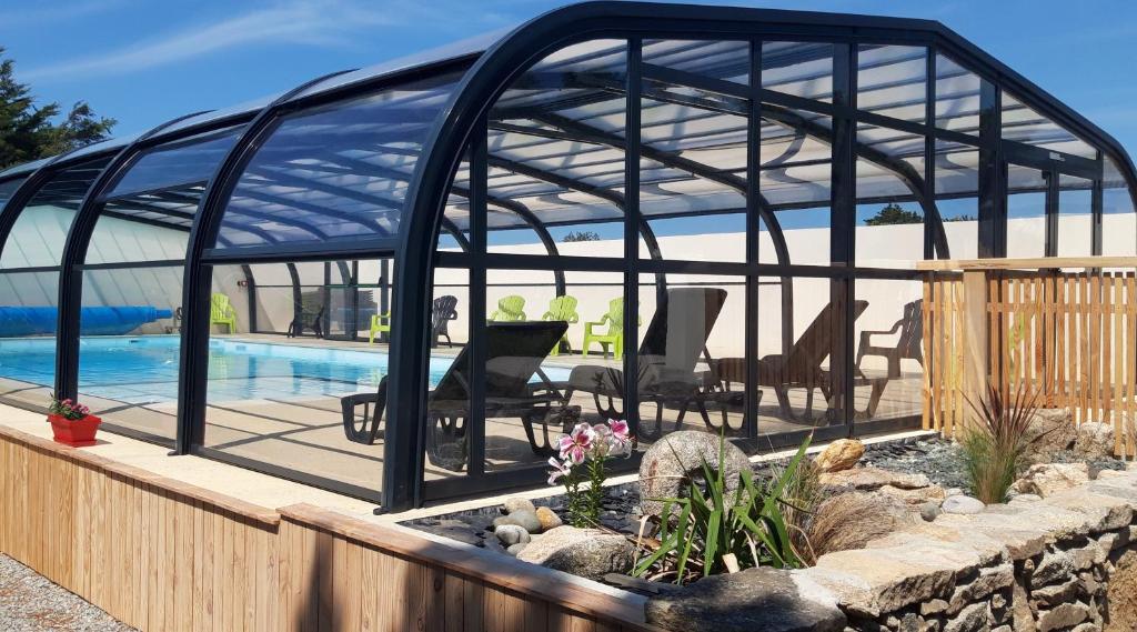 une maison en verre avec une piscine et une terrasse dans l'établissement Camping les vergers de Squividan ***, à Tréffiagat