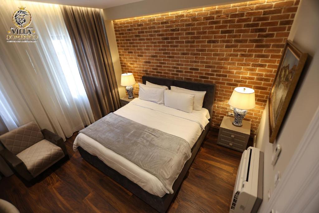 a bedroom with a bed and a brick wall at Villa Domenico Korce in Korçë