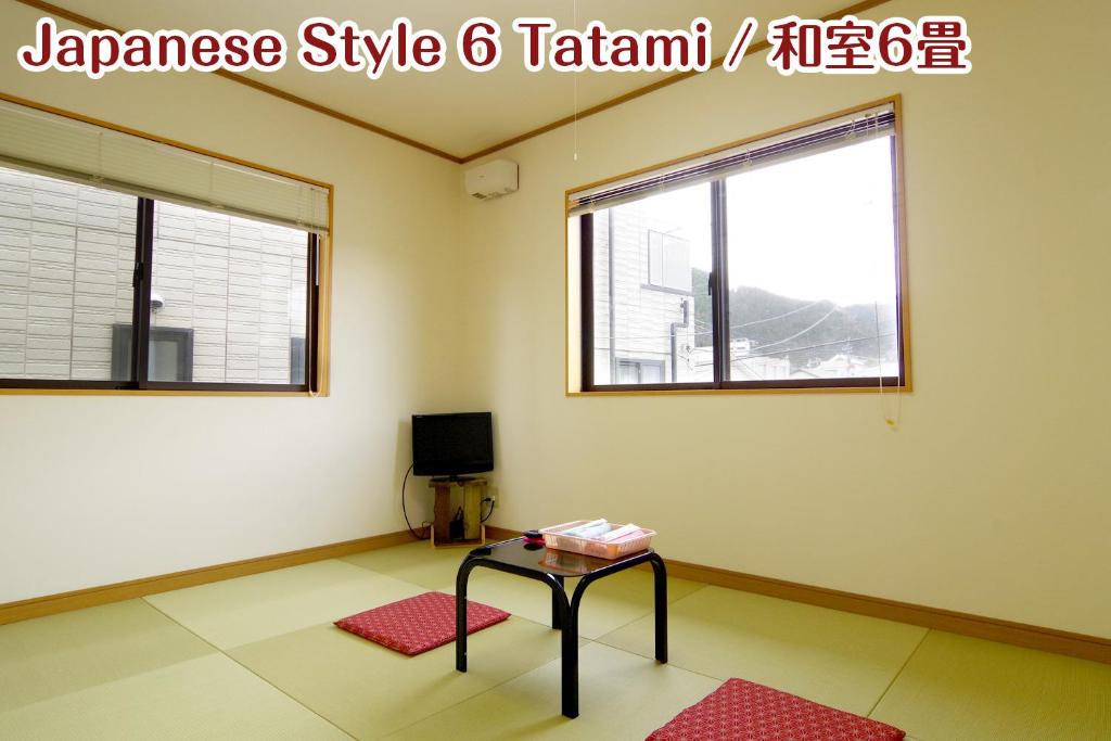 日光市にあるNIKKO stay house ARAI - Vacation STAY 13830vのテーブルと窓2つが備わる客室です。