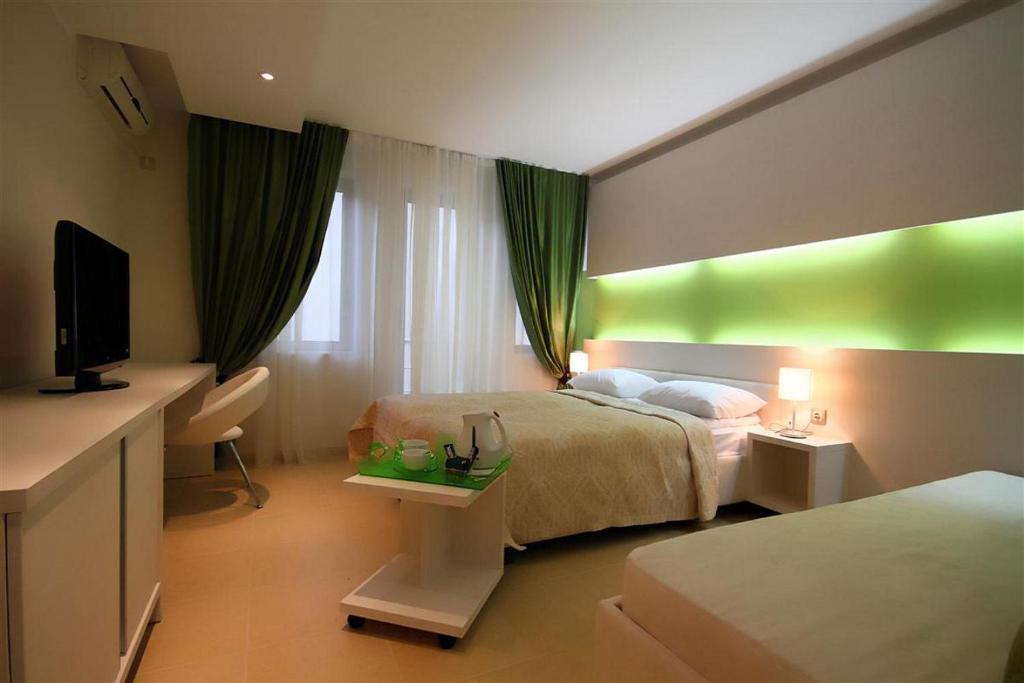 a hotel room with two beds and a flat screen tv at Domador Rooms & Apartments in Budva