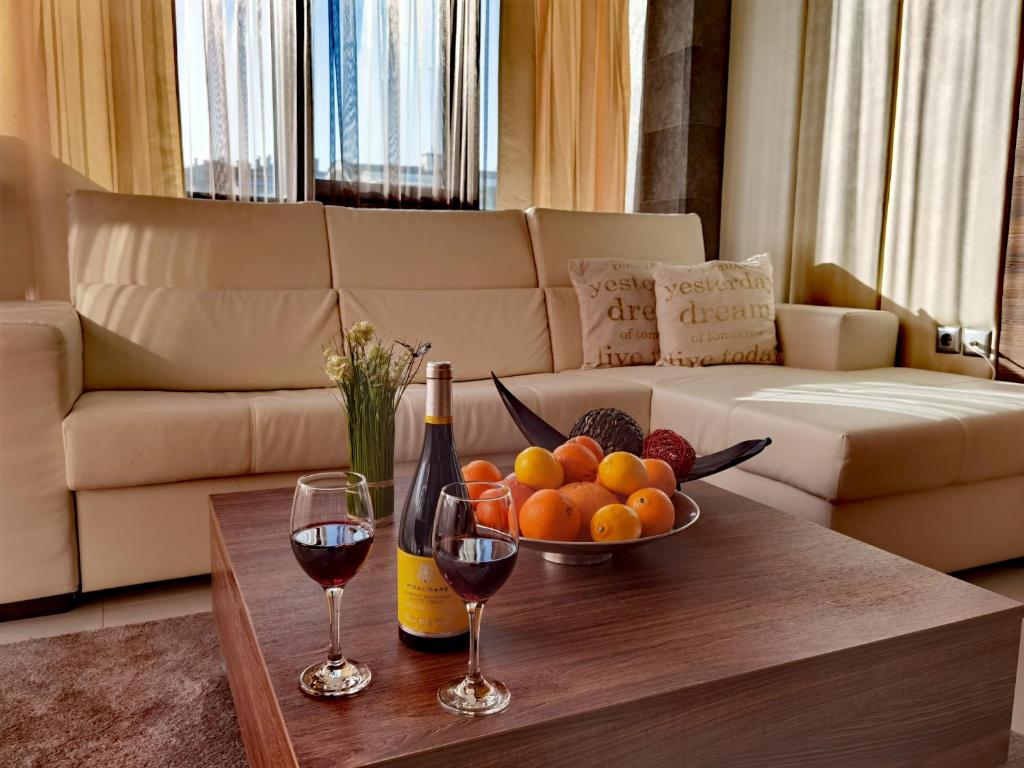 a table with a bowl of fruit and two glasses of wine at Hotel Acktion in Shumen