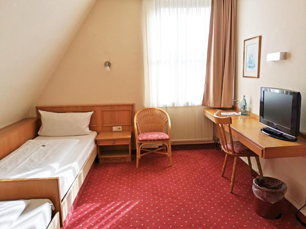 a hotel room with a bed and a desk and a computer at Landhotel Ölmühle in Mömbris