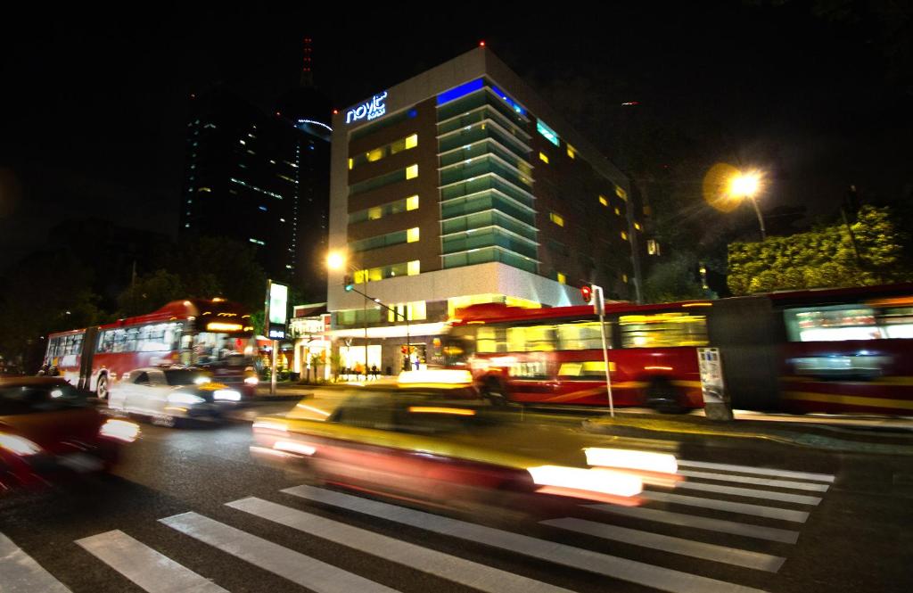una trafficata strada di notte con autobus e auto di Hotel Novit a Città del Messico