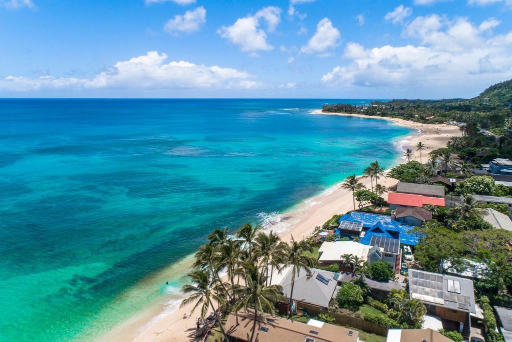 an aerial view of a beach with palm trees and the ocean at Hawaii Oceanfront Beach House Paradise on the Beach Family Activities in Haleiwa