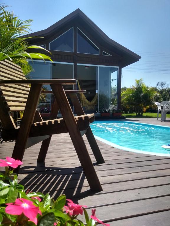 um deque de madeira com um banco ao lado de uma piscina em Villa Suhr Cabanas na Praia do Rosa