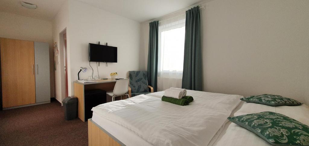 a hotel room with a bed and a desk and a window at Penzion Amfík Bukovina in Popovice