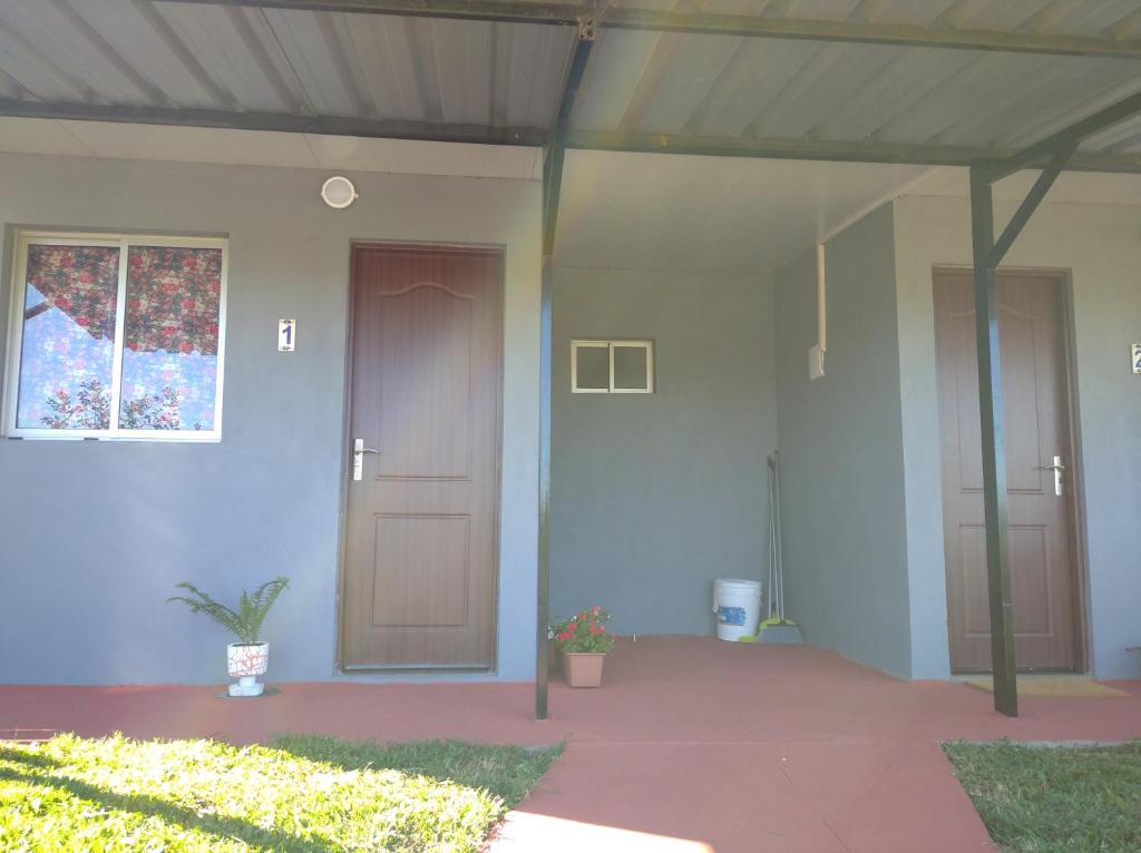 ein Haus mit zwei Türen und einer Veranda mit einer Pflanze in der Unterkunft La Comarca in Colonia del Sacramento