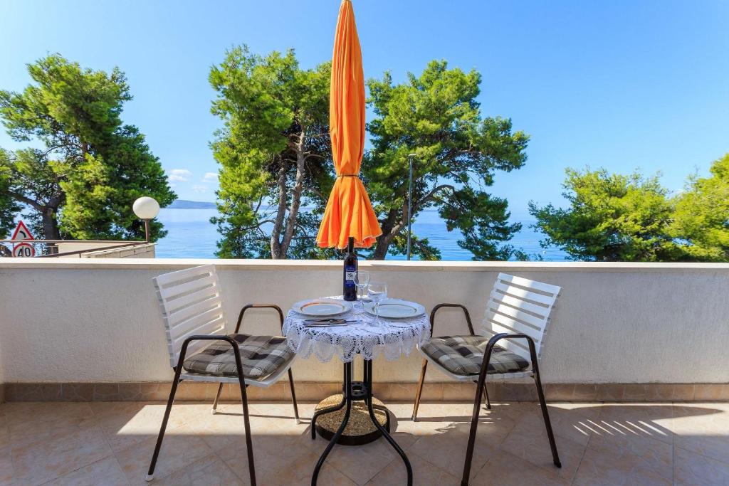 stół z 2 krzesłami i parasol na balkonie w obiekcie Apartments Verica - 15 m from beach w mieście Krilo
