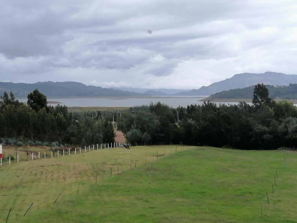 a field with trees and a body of water at Cabañas el mirador del tomine in Guatavita