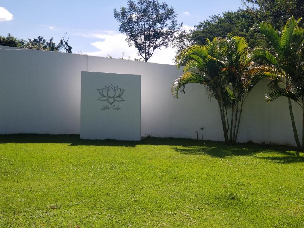 een witte muur met een bord in een tuin bij Lotus Suite in Santa Cruz de la Sierra
