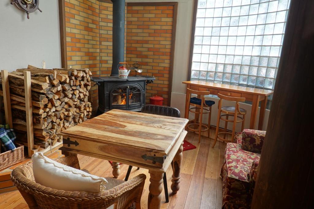 uma sala de estar com uma mesa de madeira e uma lareira em Il Bosco em Hakuba