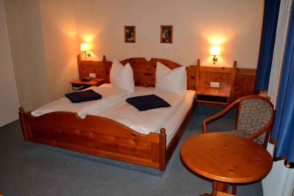 a bedroom with a large wooden bed and a chair at Hotel Walfisch in Haßfurt