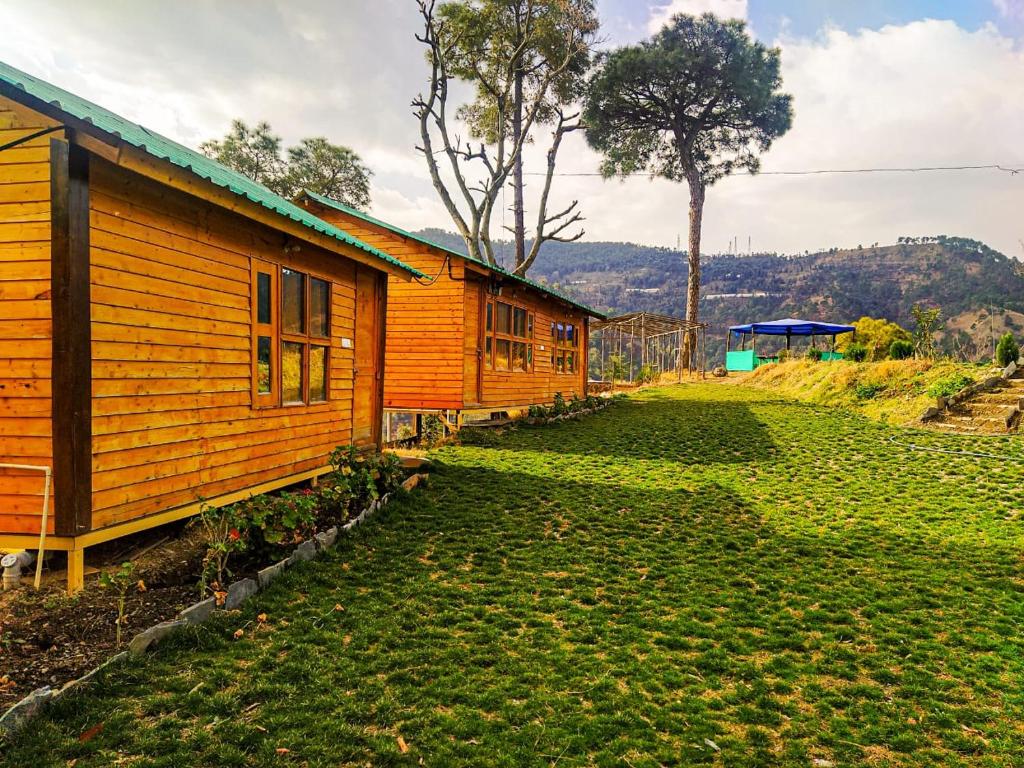 a couple of buildings sitting next to a grass field at Golden valley cottages, Chail in Chail