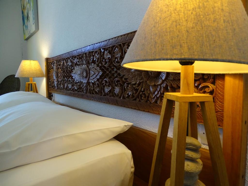 a bedroom with a bed with a lamp next to it at Hôtel Résidence Le Phoenix in Saint-Pierre