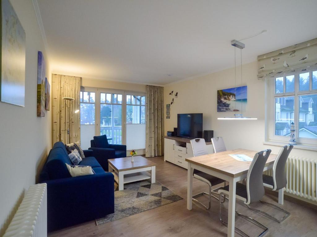 ein Wohnzimmer mit einem blauen Sofa und einem Tisch in der Unterkunft Dünenpark Binz - Komfortplus Ferienwohnung mit 1 Schlafzimmer und Balkon im Obergeschoss 214 in Binz