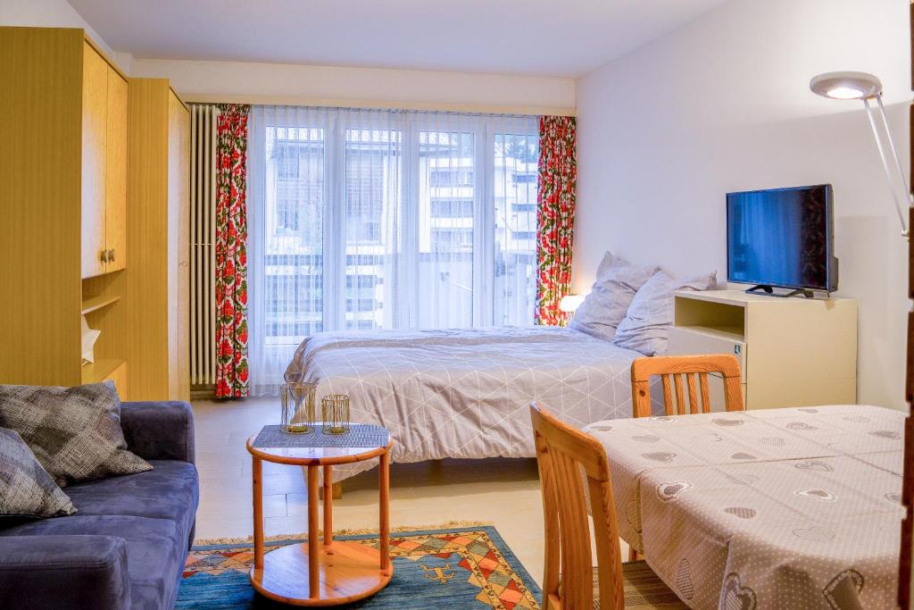1 dormitorio con 1 cama y sala de estar con sofá en Willkommen-Gemütlich, Balkon, Parkplatz direkt in St Moritz, en St. Moritz