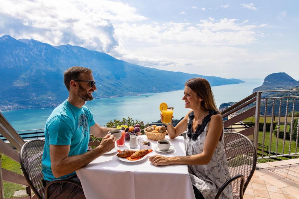 トレモージネ・スル・ガルダにあるHotel Le Balze - Aktiv & Wellnessの食べ物を食べる男女