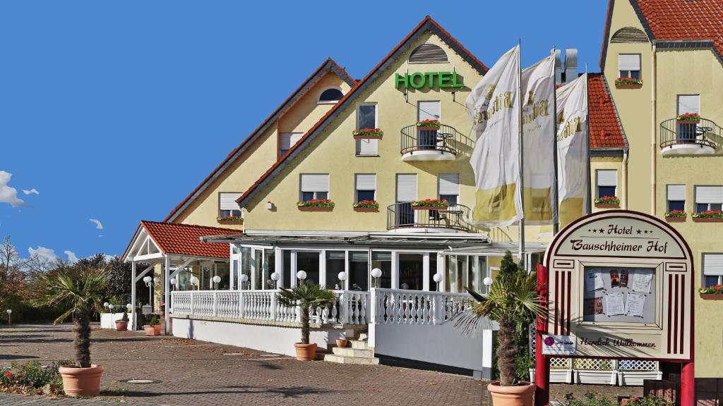 a hotel on a street with palm trees in front of it at Hotel Bauschheimer Hof in Rüsselsheim