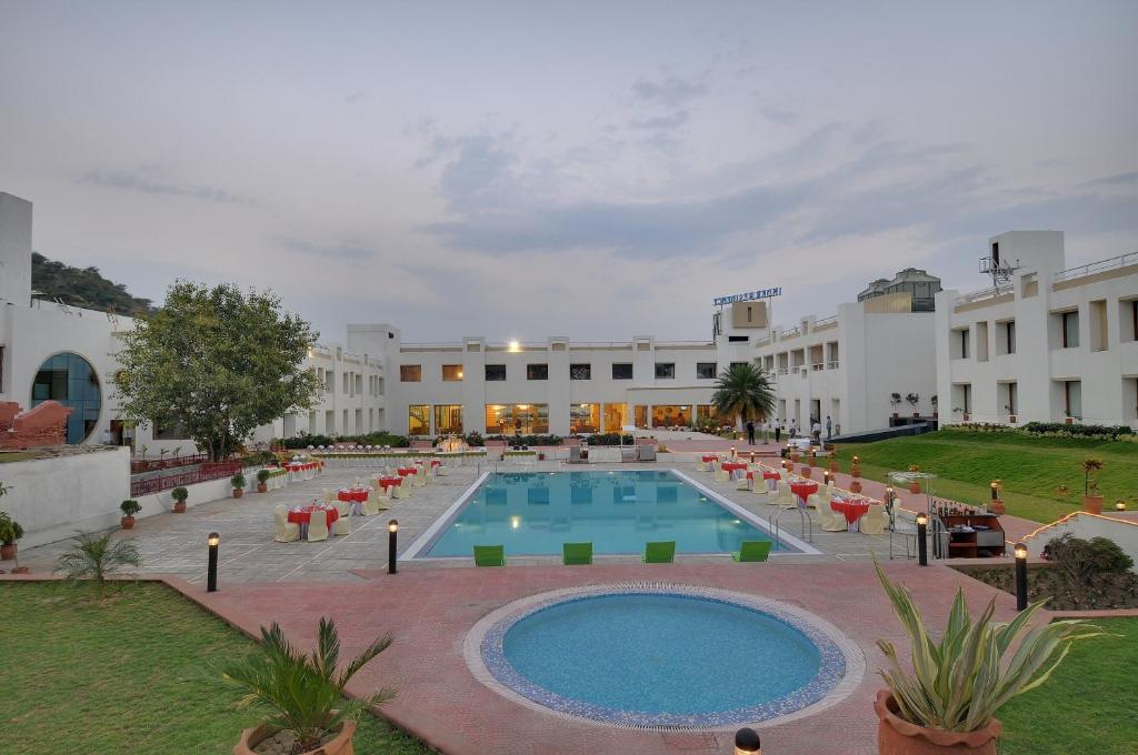 Inder Residency Resort & Spa Udaipur في أودايبور: ساحة مع مسبح امام مبنى