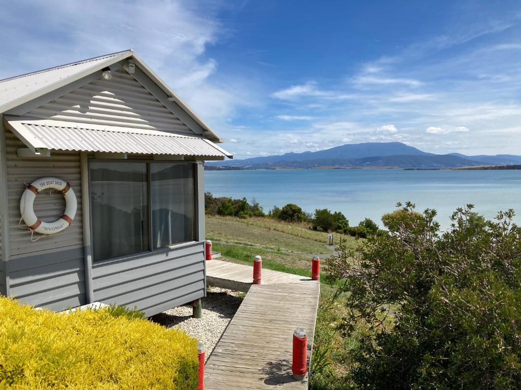 a small house with a dock next to a body of water at The Boat Shed in Sandford