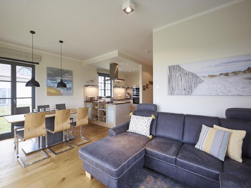 uma sala de estar com um sofá e uma sala de jantar em Reetland am Meer - Premium Reetdachvilla mit 3 Schlafzimmern, Sauna und Kamin E19 em Dranske