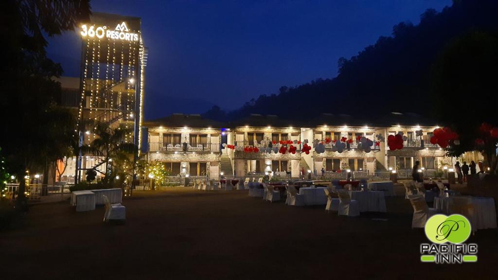 a large building with white tables and chairs at night at Pacific Inn Resort Rishikesh in Rishīkesh