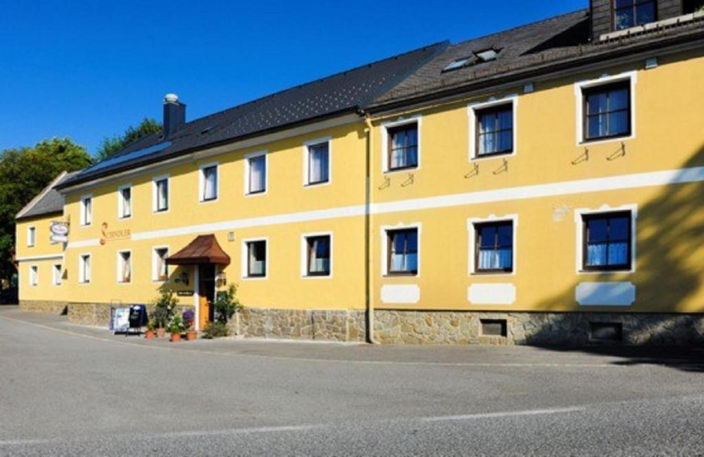 a large yellow building with a black roof at Gasthof Schindler in Brunn am Walde
