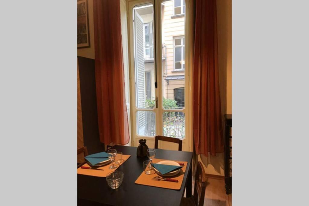 une salle à manger avec deux tables et une fenêtre dans l'établissement Loft Il Teatrino nel cuore pulsante di Torino, à Turin