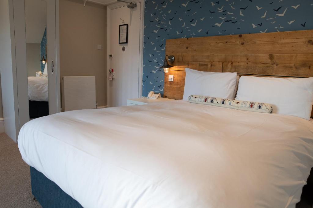 a bedroom with a large white bed with a blue wall at The Randolph Hotel in Southwold